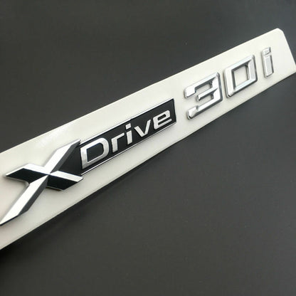 BMW X3 X4 X5 X6 1x LOGO X DRIVE 3.0 DECORATIVO CROMATO E NERO ADESIVO AUTOELEGANCERICAMBI